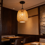 Lattice barrel pendant lit over a wooden table with a rough stone wall behind