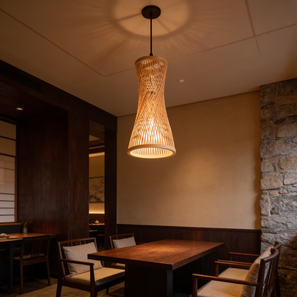 Narrow woven bamboo pendant casting warm light against a stone restaurant wall