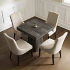 Square pedestal table seen straight on with a small dish and cream chairs