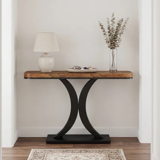 Rustic wood console with a white lamp and dried stems above a patterned runner