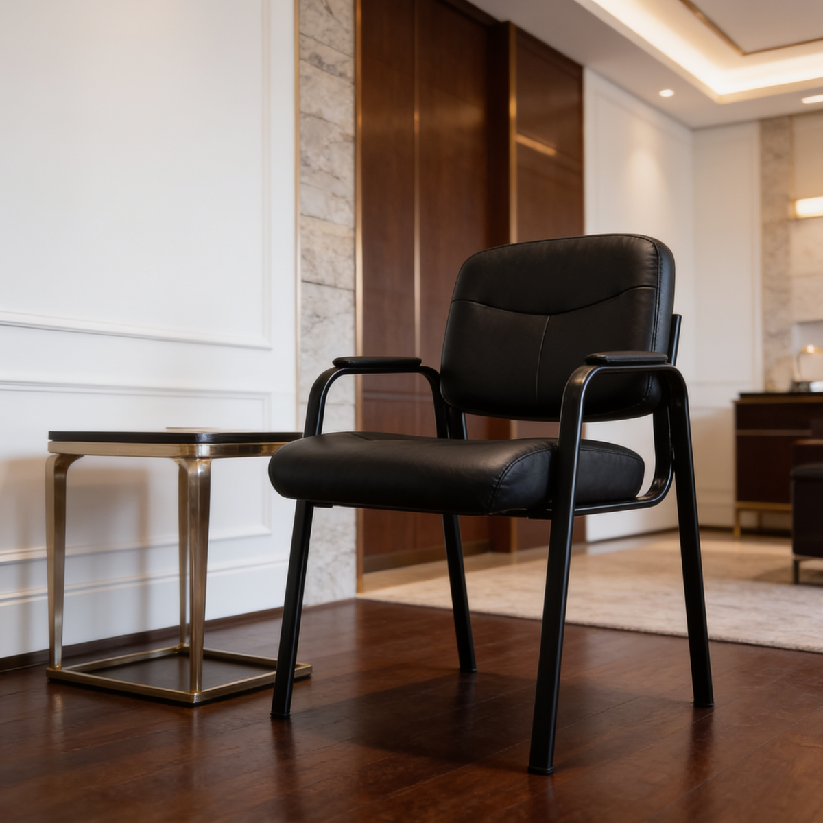 Black padded guest chair beside a small side table in an office lobby