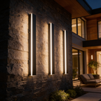 Linear outdoor wall lights glowing on a dark stone wall beside a patio seating area