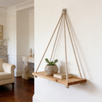 Rope shelf mounted above an armchair with a single potted plant on the board