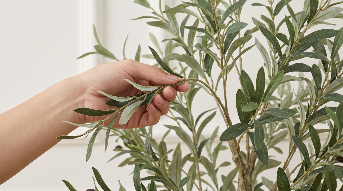 Hand bending a branch of a faux olive tree