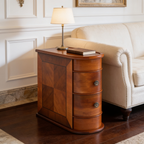 Wood pivot drawer table between a sofa and armchair under a lit table lamp