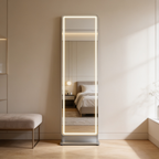 Lit full length mirror leaning on a bedroom wall beside an upholstered bench