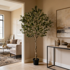 Tall faux olive tree in a black pot between a pale sofa and a dark console table