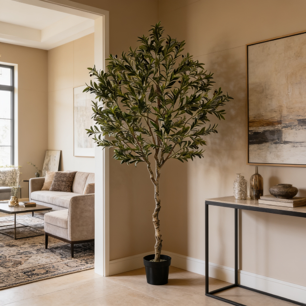 Tall faux olive tree in a black pot between a pale sofa and a dark console table