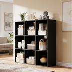 Cube bookcase against a wall beside a sofa filled with boxes and a round vase