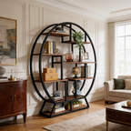 Round black iron bookcase with staggered wood shelves beside a wood sideboard