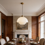 Two opal glass pendants above a long dining table near a fireplace