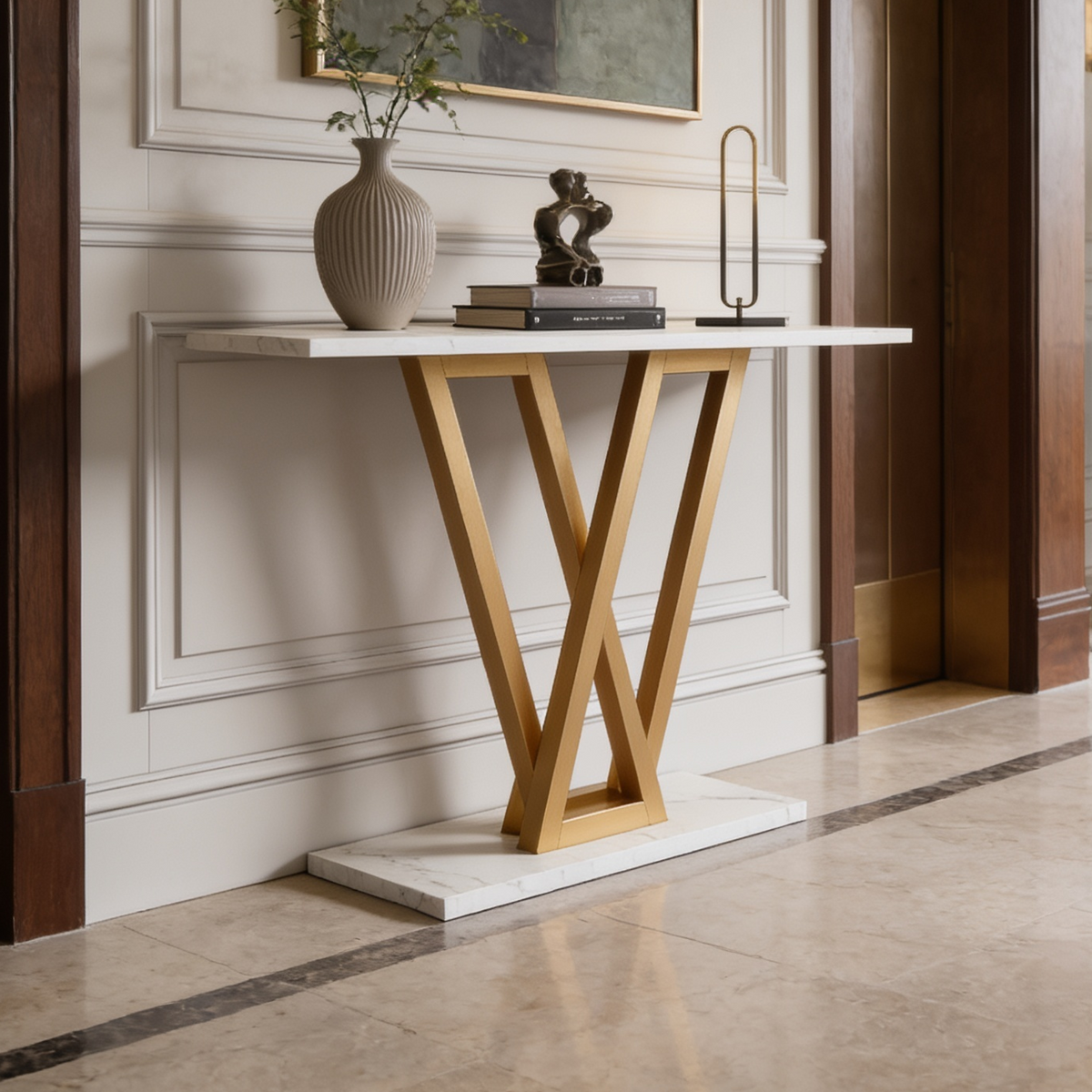 White top console on a gold V base holding vases and a small lamp in a hall