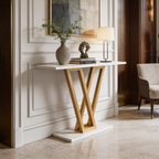Gold and white entryway console with a table lamp, vase and plant beside chairs