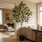 Silk leaf olive tree in a living room with an armchair, console and window behind