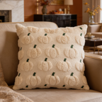 Cream tufted cushion covered in raised pumpkins on a sofa by a stone fireplace