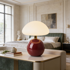 Deep red mushroom lamp lit on a dark wood nightstand