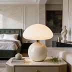 Cream mushroom lamp casting warm light on a nightstand in a green bedroom