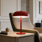 Red domed cordless lamp lit on a console next to a green armchair