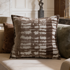 Brown and cream mottled pillow beside an olive velvet cushion on a sofa