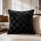 Black checkerboard woven cushion in bright sunlight against a marble wall