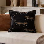 Black cushion scattered with small gold leopards next to a rust cushion