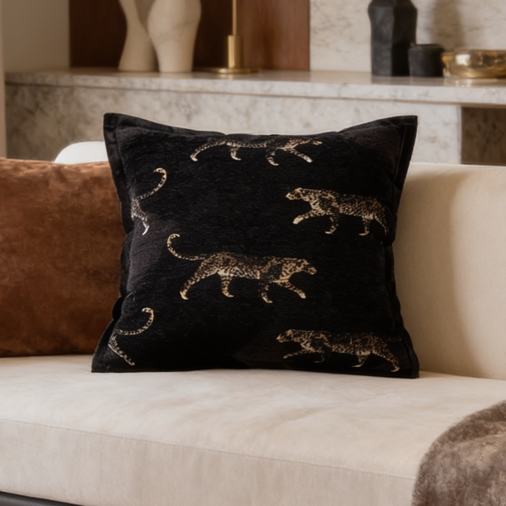 Black cushion scattered with small gold leopards next to a rust cushion
