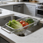 Mesh sink strainer spanning a stainless sink with broccoli and tomatoes beside a dishwasher