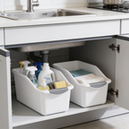 Under sink cabinet with two white bins arranged either side of the drain pipe