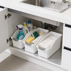 Low angle of white bins holding cleaning bottles and sponges under a kitchen sink