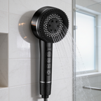 Black handheld shower head spraying water against a tiled shower wall