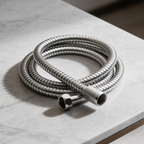 Coiled chrome flexible shower hose lying on a marble counter