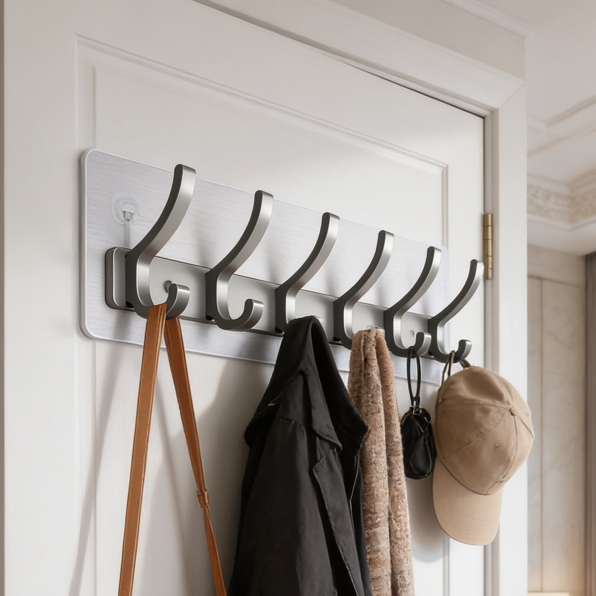 Gray metal hook rail on a door with a coat tote bag and cap hanging from it