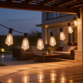 Cafe string lights strung under a wooden pergola above outdoor lounge seating