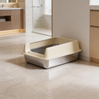 Beige rimmed stainless litter box on pale tile with kitchen cabinets behind
