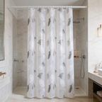 Leaf print bath curtain drawn over a white tub in a marble tiled bathroom