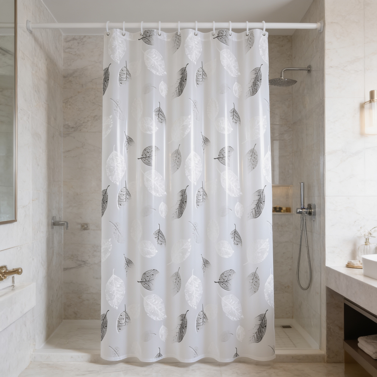 Leaf print bath curtain drawn over a white tub in a marble tiled bathroom