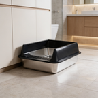 Black rimmed litter box with a stainless basin set against a wooden cabinet