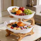 Two tier white snack stand with fruit above and candy and nuts below on a countertop