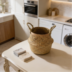 Seagrass belly basket on a laundry floor beside folded towels