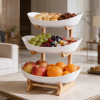 Two tier white oval serving stand on a wooden frame holding grapes, apples and oranges