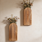 Wooden wall vase holding pink dried blooms against a paneled wall
