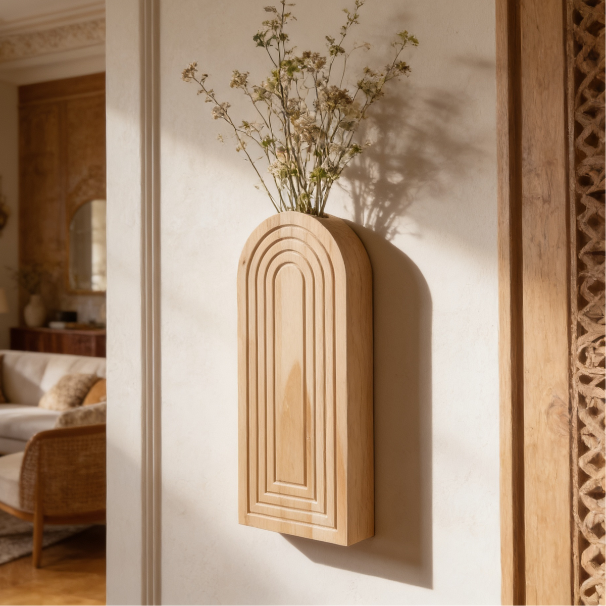 Wall mounted wood vase with tall dried branches beside a slim mirror