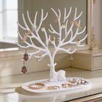 White stand hung with earrings and necklaces above bracelets in its tray