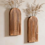 Two arched wall vases hung at different heights with dried grasses