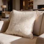 Ivory cushion with a soft floral weave and rope trim on a cream sofa near a fireplace
