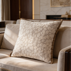 Tan cushion woven with big leaf shapes and a corded seam on a cream couch