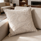 Ivory cushion with a dense raised flower jacquard on a pale sofa in a wide room