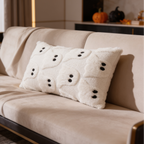 Cream lumbar pillow with quilted ghost faces against a sofa back