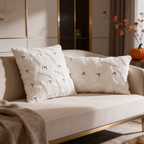 Pair of cream ghost pillows on a sofa with pumpkins and fall branches nearby