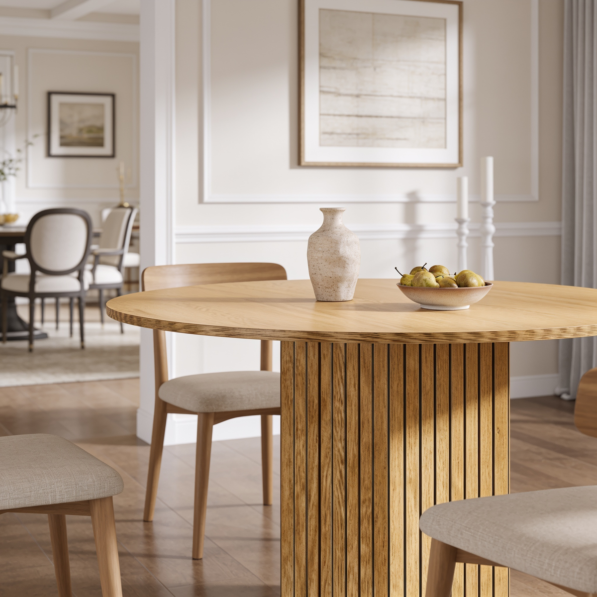 Light oak round table on a fluted cylinder pedestal below framed wall art